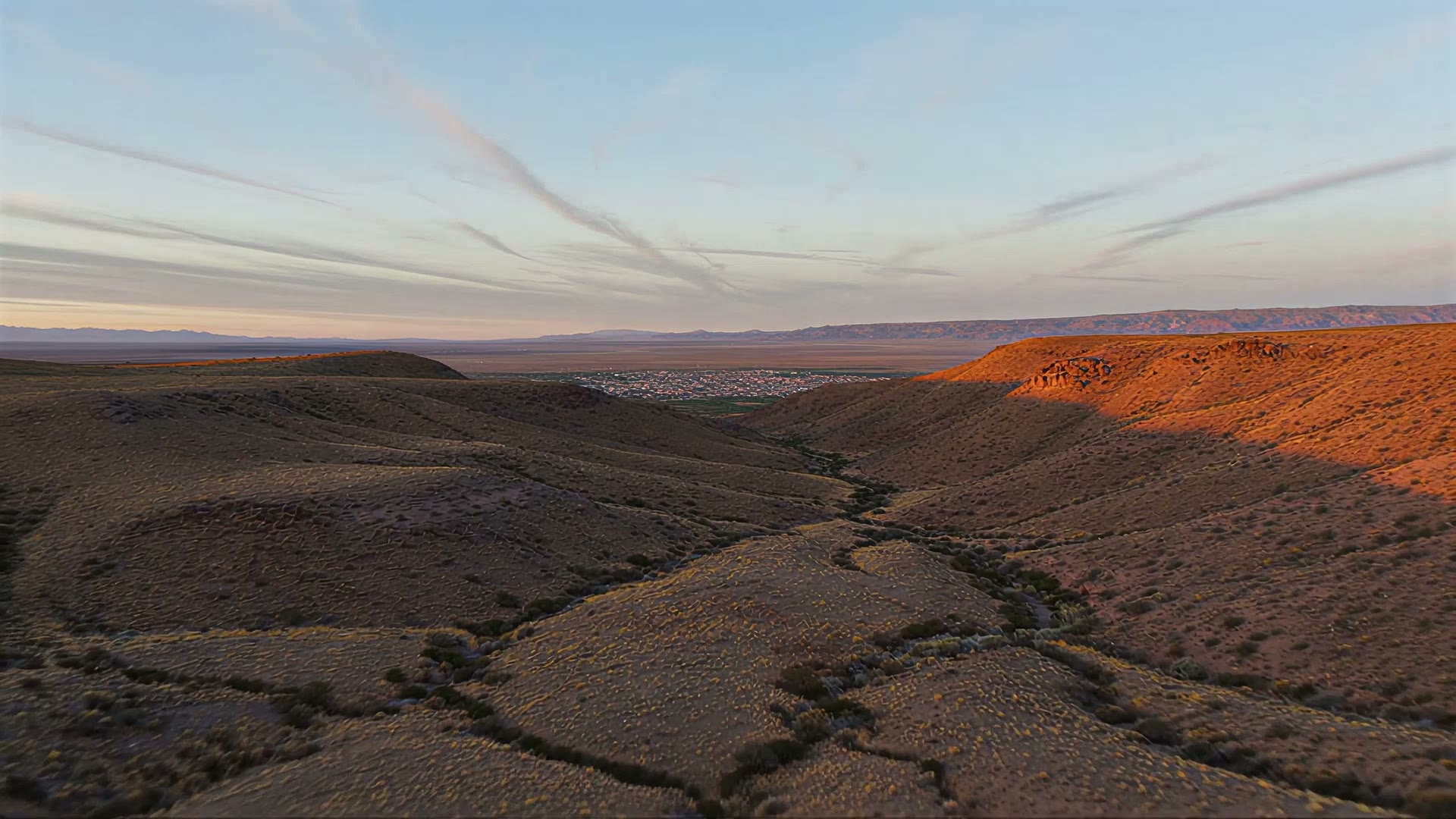 Vista aérea de cerros de secano de la Región de Coquimbo al atardecer, con un pueblo al fondo del valle